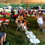 people gathered under a tent in seats