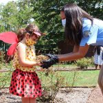 young girl in ladybug costume taking a plant