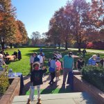 little girl standing on steps with people in the background and fall foliage