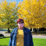 woman standing in front of yellow and green fall trees