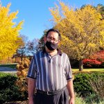 man with mask standing in front of fall foliage