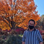 man with mask standing in front of orange tree