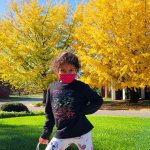 young girl posing in front of yellow and green trees