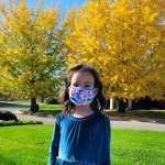 young girl standing in front of yellow and green tree