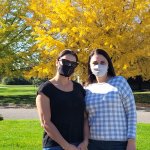 two women standing in front of yellow tree