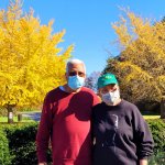 two people standing in front of autumn trees