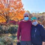 couple standing in front of orange leaves tree