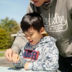 man and boy holding paintbrush with praying mantis on it