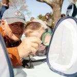 older man and young buy looking through a magnifying glass at a praying mantis