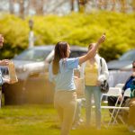 woman holding up something to show crowd outside in garden