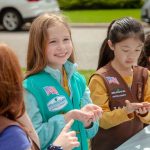 young girls girl scouts holding small praying mantis in hand