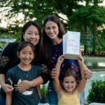 family holding floating lantern with handwritten message outside in front of fountain