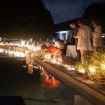 people placing floating lanterns into fountain outside with lights