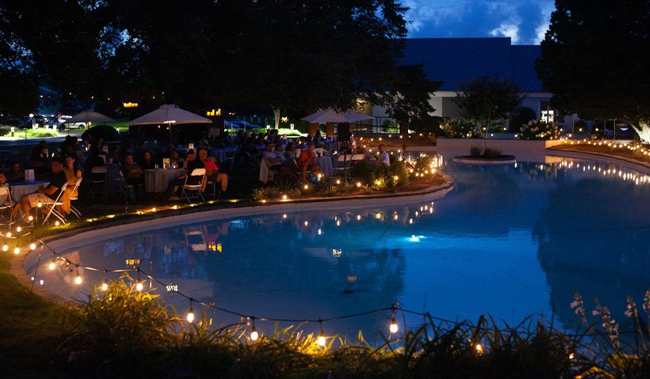 People sitting at tables outdoors with fountain and lights