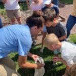 children look at bag full of ladybugs outside in garden