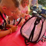 children look at ladybugs in a case with magnifying glass