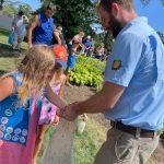 young girls take handful of ladybugs out of bag outside in Pinelawn garden