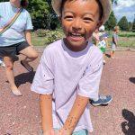 young boy holding a handful of ladybugs outside in garden