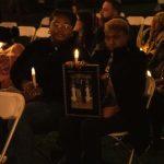 people sitting with memorial photo and candles