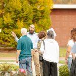 man speaking to group of people outside