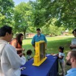 people looking at beehive behind glass case