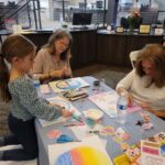 two woman and young girl working on art project at a table