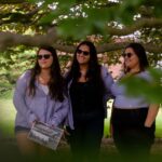 photo of three women posing for picture surrounded by tree branches