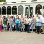 photo of people posing in front of an old fashioned trolley