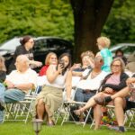 people in seats watching a show taking photos and videos