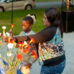 woman and child placing a rose into a vase