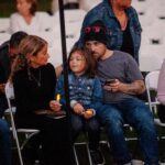 family with small child sitting outside in chairs holding candles