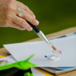 close up of a hand dipping a paint brush into paint