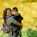 woman and child smiling in front of beehive backdrop
