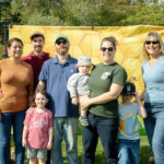 large family smiling in front of beehive backdrop